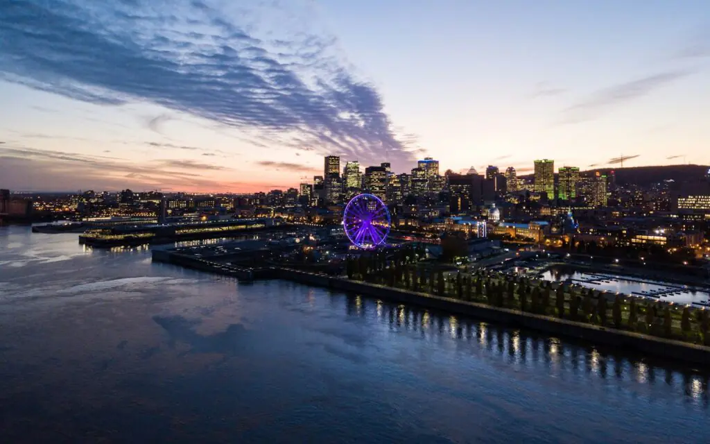 Montreal's Old Port at dusk with the lit ferris wheel, downtown skyline, and Mount Royal beyond